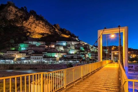 Illuminated Ottoman houses and modern bridge over Osum river at dusk