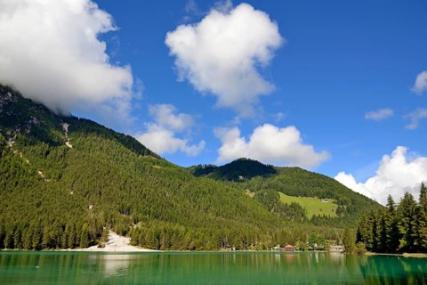 View over the emerald green lake Dobbiaco with mountain forest and Murengang