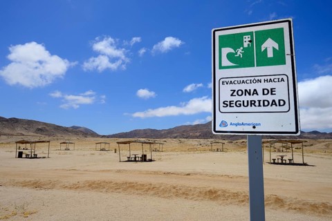 Tsunami warning sign near picnic area on the beach