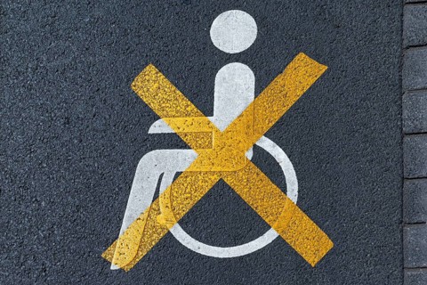 Crossed out disabled sign on a parking lot