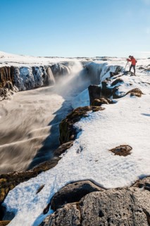 Photographing man at the edge of the Selfoss waterfall in winter
