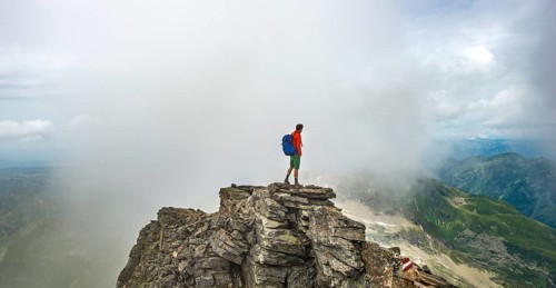 Hiker on the summit of the Hochgolling with rising fog