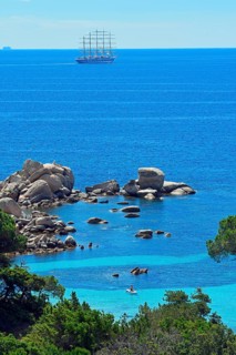 Palombaggia beach with turquoise blue sea and sailing ship