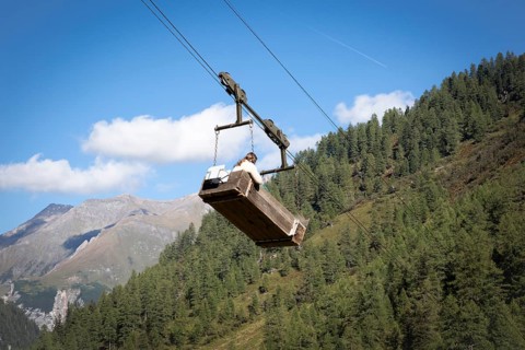 A woman travels in the material cable car of the Litzlhofalm in the Seidwinkl valley in the Hohe Tauern National Park