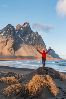 Man in red jacket stretches arms into the air