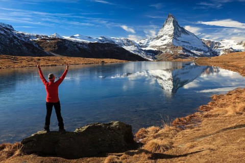 A woman stands with her arms outstretched on a rock