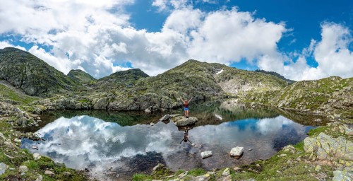 Hiker on a stone in a small lake
