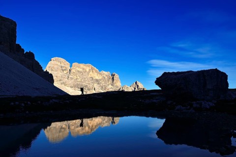 Hiker on the lake in the backlight