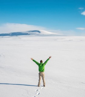 Young man stands alone in snowy landscape