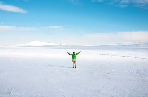 Young man stands alone in snowy landscape