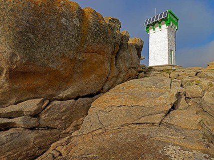 Green and white lighthouse on granite rocks