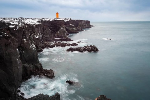 Orange lighthouse Ondverdarnes stands on a dark cliff