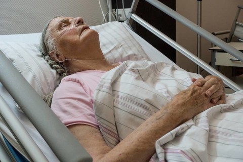 Sleeping senior citizen with respiratory tube in bed in hospital