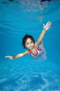 Little girl learns to swim underwater in the pool
