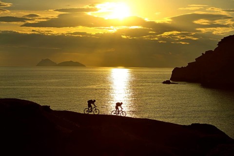 Two mountain bikers cycling on a rocky coast