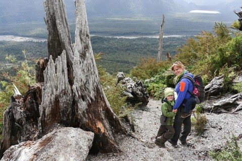 Woman with child hiking on crater of volcano Chaiten and volcanic eruption destroyed forest