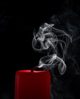 Smoky candle in front of a black background