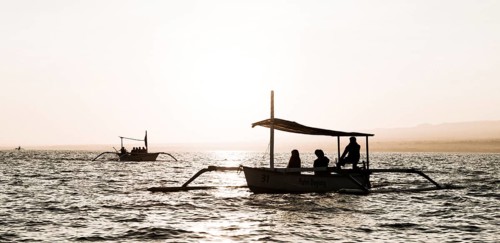 Silhouettes of outrigger boats in the ocean at sunrise