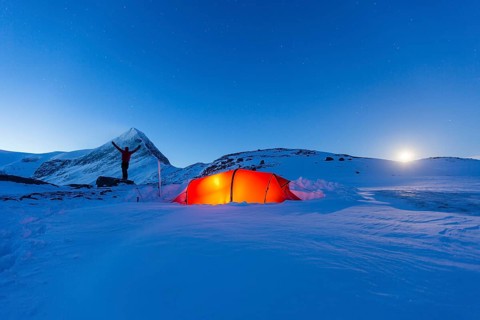 Tent with person at full moon in the snow