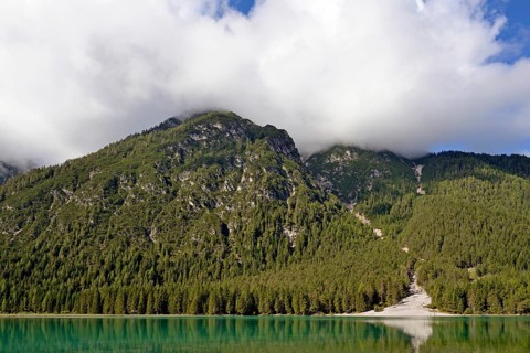 View over the emerald green lake Dobbiaco with mountain forest and Murengang