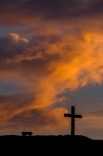 Summit cross with bank and dramatic clouds at sunrise