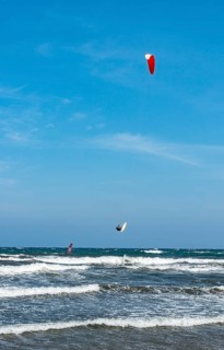 Kitesurfer in the air over sea with waves