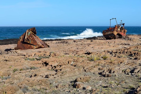 Rusty wreck of a fish trawler on the rocky shore