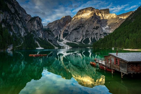 Green mountain lake with boats and boathouse