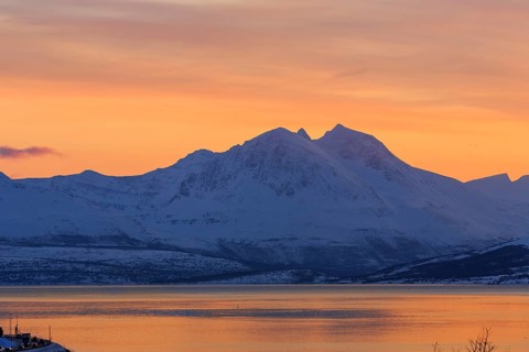 Tromsoysund with snowy mountains at sunset