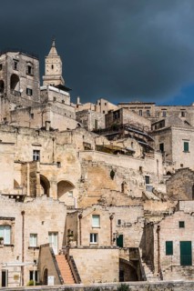 Houses with cathedral Maria Santissima della Bruna with dark cloudy sky