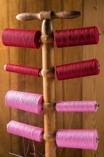 Thread stand in front of wooden wall with cotton thread reels