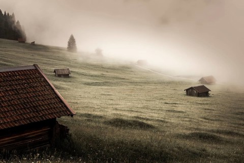 Small cabin on mountain meadow in the fog
