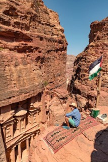 Tourist sits on a carpet and looks from above into the gorge Siq