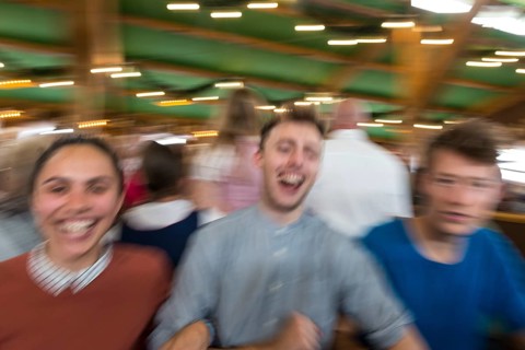 Three young people celebrate happily in a beer tent