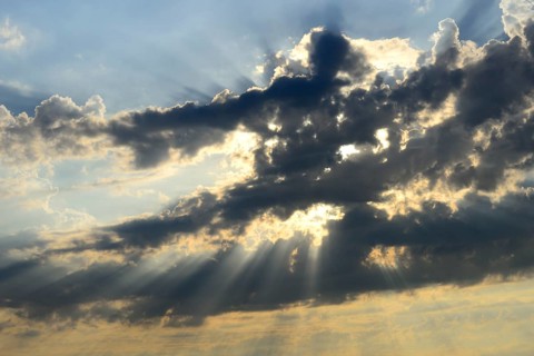 Sun shining behind dark clouds