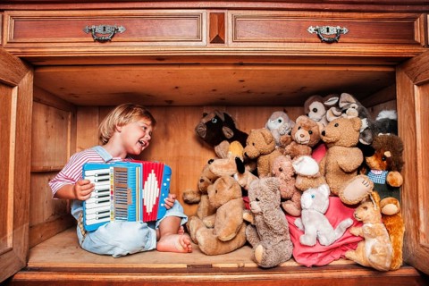 Five year old girl playing accordion for her stuffed animals