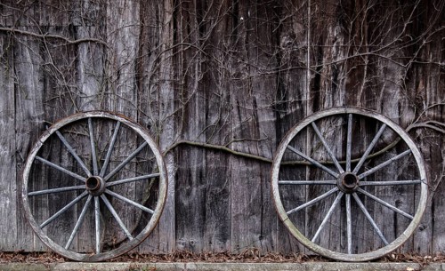 Two wagon wheels leaning against a barn wall