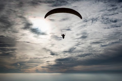 Paraglider against cloudy sky
