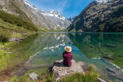 Female Hiker with sun hat sitting on shore