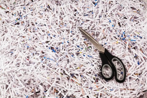 Black scissors on top of strips of shredded paper