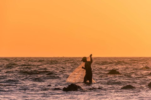 Local fishermen with fishing net in backlight