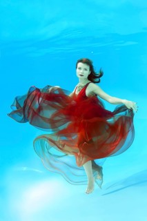 Young woman with red dress posing under water