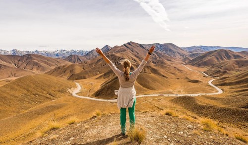 Woman looking at stark mountain landscape with mountain road
