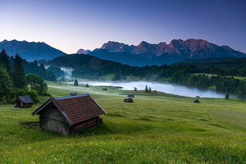 Small cabin on mountain meadow at forest edge