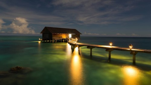 Wooden hut on stilts in lagoon at night