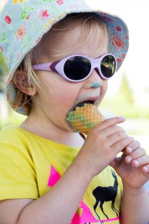 Toddler with sunglasses licking ice cream