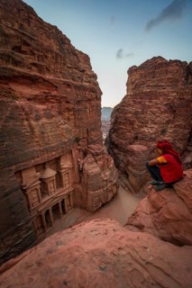 Bedouin sits at the edge of a rock and looks from above into the gorge Siq