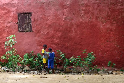 Two children in front of a red house facade