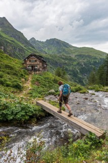 Hiker crosses wooden bridge across mountain stream