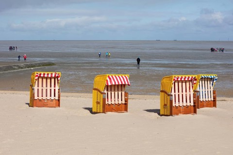 Beach chairs on sandy beach and back mudflat strollers